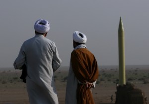 Iranian clerics stand near surface to surface missile which is ready to be launched during war game near city of Qom