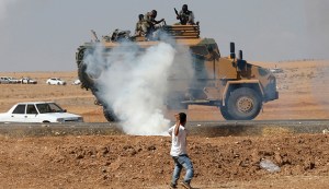 A protester throws stones at an armoured army vehicle during a pro-Kurdish demonstration, near the Mursitpinar border crossing on the Turkish-Syrian border, in Suruc