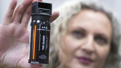An employee at a gunsmiths and indoor shooting range in Tel Aviv shows pepper spray to a customer on October 13, 2015 (Jack Guez/AFP)