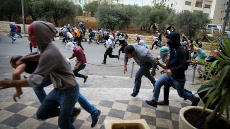 Palestinian protesters hurling stones at Israeli troops (not seen) during riots near the Jewish settlement of Bet El, near the West Bank city of Ramallah, October 10, 2015. (Flash90)