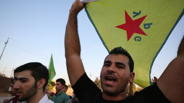 In this Saturday, July 25, 2015 file photo, a demonstrator waves the People's Protection Units flag, known as YPG, which is the main Kurdish fighting force in Syria, during a demonstration in Irbil, the Northern Kurdish region of Iraq. (AP Photo/Bram Janssen)