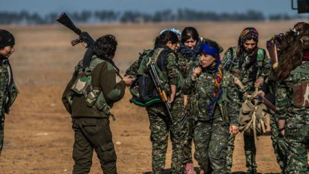 In this photo released on May 24, 2015, provided by the Kurdish fighters of the People’s Protection Units (YPG), which has been authenticated based on its contents and other AP reporting, Kurdish female fighters of the YPG carry their weapons as they prepare for a battle against Islamic State fighters near the village of Mabrouka, northeast Syria. (The Kurdish fighters of the People's Protection Units via AP)