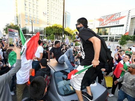 Protesters climb atop a car stopped in traffic as a crowd marches near the venue where Republican presidential candidate Donald Trump was speaking during a rally in San Jose, California on June 2, 2016. Protesters who oppose Donald Trump scuffled with his supporters on June 2 as the presumptive Republican presidential nominee held a rally in California, with fistfights erupting and one supporter hit with an egg. / AFP / JOSH EDELSON (Photo credit should read JOSH EDELSON/AFP/Getty Images)