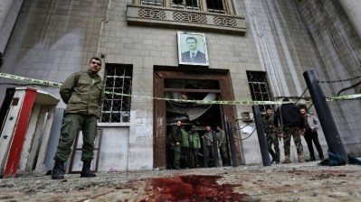 Syrian security forces gather under a portrait of Syrian President Bashar Assad at the old palace of justice building in Damascus following a reported suicide bombing on March 15, 2017. (AFP Photo/Louai Beshara)