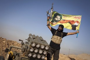 An Iraqi militia fighter of the Shiite cleric Muqtada al-Sadr's Saraya al-Salam (Peace Brigade), waves a flag next to a rocket launcher during heavy clashes with IS fighters in Tuz Khurmatu in the Salaheddin province on August 31, 2014. (photo credit: AFP/J.M. Lopez)