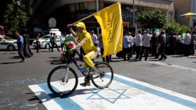 An Iranian man rides his bicycle on top of a reproduction of an Israeli flag painted on the street during a rally marking al-Quds (Jerusalem) Day in Tehran on June 23, 2017. (AFP Photo/Stringer)