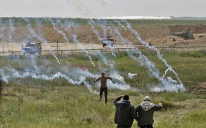 A picture taken on March 30, 2018 shows Palestinians fleeing as tear gas grenades begin to drop during a demonstration near the border with Israel east of Gaza City to commemorate Land Day. (AFP/Mahmud Hams)