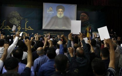 Hezbollah leader Sheik Hassan Nasrallah speaks on a screen via a video link during a ceremony to mark the second anniversary of the death of Hezbollah top commander, Mustafa Badreddine, who was killed in an explosion in Damascus, in the southern suburbs of Beirut, Lebanon, Lebanon, on May 14, 2018. (AP Photo/Bilal Hussein)