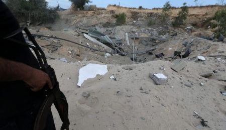 A Palestinian militant stands guard near the destroyed Islamic Jihad military base after it was targeted by an Israeli warplane, the southern Gaza Strip May 30, 2018. REUTERS/Ibraheem Abu Mustafa
