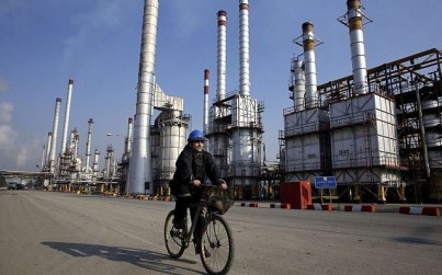 An Iranian oil worker rides his bicycle near an oil refinery south of the capital, Tehran, December 22, 2014. (AP/Vahid Salemi)