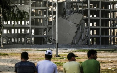 Palestinian youths look at a building that was damaged by an Israeli air strike in Gaza City on July 14, 2018 ( AFP PHOTO / MAHMUD HAMS) Palestinian youths look at a building that was damaged by an Israeli air strike in Gaza City on July 14, 2018 ( AFP PHOTO / MAHMUD HAMS)