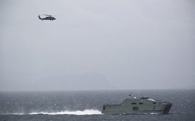 In this Tuesday, March 21, 2017 photograph, an Omani naval vessel sails alongside the USS George H.W. Bush as it travels through the Strait of Hormuz.  (AP Photo/Jon Gambrell)
