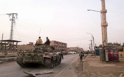 Members of the pro-Syrian government forces ride on a tank as it drives down a street in the Syrian border town of Albu Kamal, on November 20, 2017. (AFP/ STRINGER)