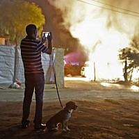 A man watches a building that was set ablaze after it was hit by a rocket fired from the Gaza Strip, in the southern Israeli town of Sderot on November 12, 2018. (Menahem KAHANA / AFP)
