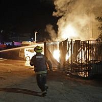 Israeli security forces and firefighters gather near a building set ablaze after it was hit by a rocket fired from the Gaza Strip, in the southern town of Sderot on November 12, 2018. (Photo by Menahem KAHANA / AFP)