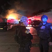 Police officers stand next to a building fire in Sderot on November 12, 2018. (Israel Police)
