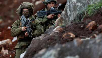 Israeli soldiers stand guard at the site of their excavation work, near the southern border village of Mays al-Jabal, Lebanon, December 13, 2018.