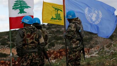 UN peacekeepers hold their flag while standing next to Hezbollah and Lebanese flags, near the border with Israel, December 13, 2018.
