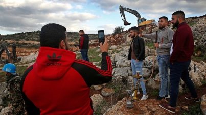 Lebanese villagers take souvenir pictures in front of Israeli excavators in the southern village of Mays al-Jaba (Photo: AP)
