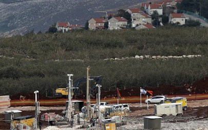 In this Thursday, Dec. 13, 2018 photo, Israeli military equipment works on the Lebanese-Israeli border in front of the Israeli town of Metula, background, near the southern village of Kafr Kila, Lebanon (AP Photo/Hussein Malla)