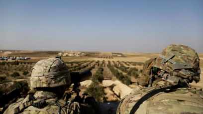 American troops look out toward the border with Turkey from a small outpost near the town of Manbij, northern Syria, February 7, 2018. 