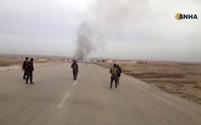 Screen capture from video provided by Hawar News, ANHA, shows Kurdish fighters standing guard at the site of a suicide attack near the town of Shaddadeh, in Syria's northeastern province of Hassakeh, Syria, January 21, 2019. (ANHA via AP)