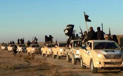In this undated file photo released online in the summer of 2014 on a militant social media account, which has been verified and is consistent with other AP reporting, terrorists of the Islamic State group hold up their weapons and wave its flags on their vehicles in a convoy on a road leading to Iraq, in Raqqa, Syria. (Militant photo via AP, File)