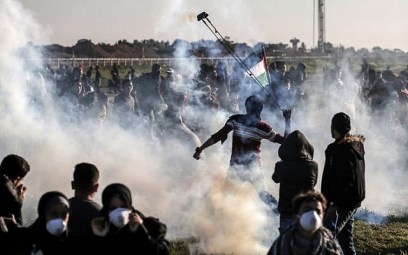 Illustrative: A Palestinian uses a slingshot to fling back a tear gas canister thrown by Israeli forces during clashes at the fence along the border with Israel, east of Gaza City, on March 8, 2019. (Mahmud Hams/AFP)