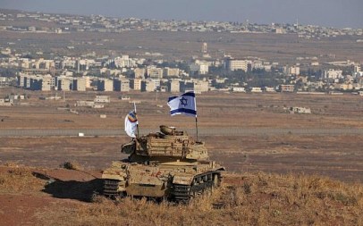 Photo taken on October 18, 2017 shows an Israeli flag fluttering above the wreckage of an Israeli tank sitting on a hill in the Golan Heights and overlooking the border with Syria. (Photo by JALAA MAREY / AFP)
