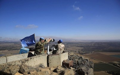 In this photo taken on Tuesday, Sept. 16, 2014, UN peacekeepers from the United Nations Disengagement Observer Force, also known as UNDOF, observe Syria's Quneitra province at an observation point on Mt. Bental in the Israeli-controlled Golan Heights, overlooking the border with Syria. .(AP Photo/Tsafrir Abayov)