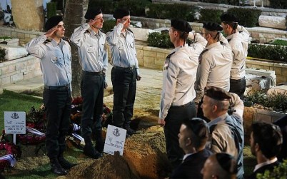 Israeli soldiers salute near the fresh grave of Zachary Baumel, during his funeral at the Mount Herzl Military cemetery in Jerusalem, April 4, 2019. (Hadas Parush/Flash90)