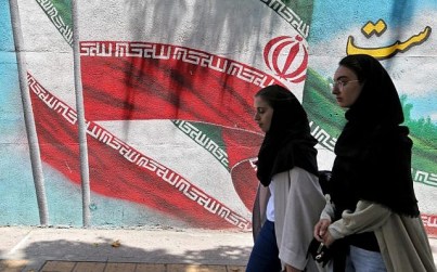 Iranian women walk past a mural painted with the Iranian flag in Tehran on June 25, 2019. (ATTA KENARE / AFP)