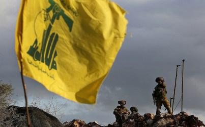 In this photo from December 13, 2018, Israeli soldiers stand guard next to cameras at their new position in front of a Hezbollah flag, near the Lebanese southern border village of Mays al-Jabal, Lebanon. (AP Photo/Hussein Malla)