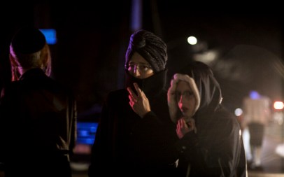 Onlookers including Orthodox Jewish stand on the corner of Forshay Road in Monsey, N.Y., Sunday, Dec. 29, 2019, down the street from the scene of a stabbing that occurred late Saturday during a Hanukkah celebration. (AP Photo/Allyse Pulliam)