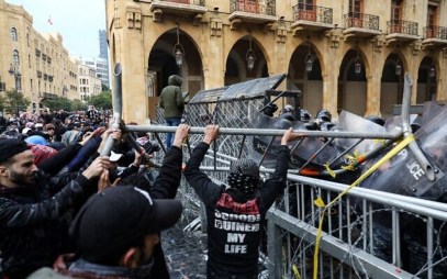 Anti-government protesters use a metal barrier to ram security forces taking cover during clashes in the central downtown district of the Lebanese capital Beirut near the parliament headquarters on January 18, 2020. (ANWAR AMRO / AFP)