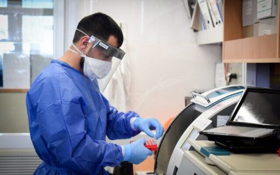 Medical team members at the Barzilay hospital, in the southern Israeli city of Ashkelon, wear protective gear, as they handle a coronavirus test sample on March 29, 2020. (Flash90)