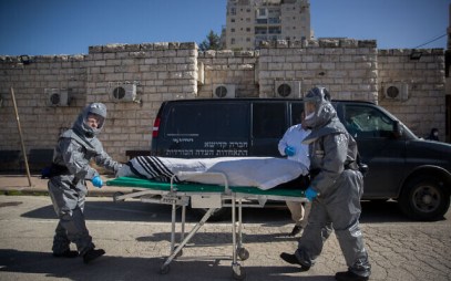Illustrative: Funeral workers wearing protective clothes carry the body of a patient who died from the coronavirus (COVID-19), at the Shamgar Funeral Home in Jerusalem on March 29, 2020. (Yonatan Sindel/Flash90)