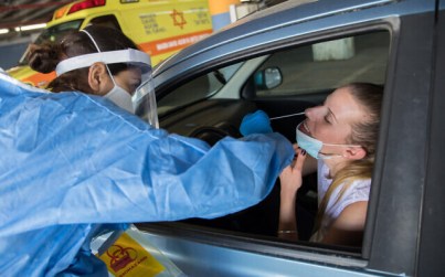 A medical team member wearing protective gear takes a swab from a woman to test for the coronavirus at Shaare Zedek hospital in Jerusalem on April 30, 2020 (Nati Shohat/Flash90)