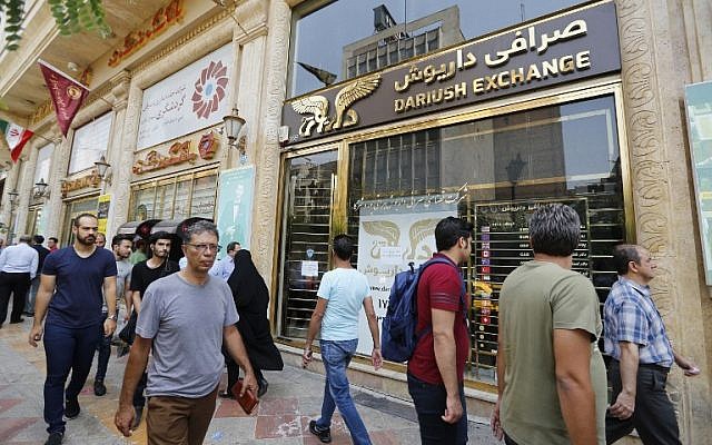 People walk in front of a currency exchange shop in the Iranian capital Tehran on August 8, 2018. (AFP PHOTO / ATTA KENARE) People walk in front of a currency exchange shop in the Iranian capital Tehran on August 8, 2018. (AFP PHOTO / ATTA KENARE)