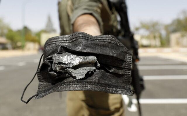 An Israeli soldier uses a mask to hold a piece of debris from a Syrian surface-to-air missile that landed near the Dimona nuclear site in Israel's southern Negev desert, on April 22, 2021. (Ahmad GHARABLI / AFP) An Israeli soldier uses a mask to hold a piece of debris from a Syrian surface-to-air missile that landed near the Dimona nuclear site in Israel's southern Negev desert, on April 22, 2021. (Ahmad GHARABLI / AFP)