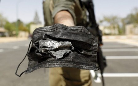 An Israeli soldier uses a mask to hold a piece of debris from a Syrian surface-to-air missile that landed near the Dimona nuclear site in Israel's southern Negev desert, on April 22, 2021. (Ahmad GHARABLI / AFP) An Israeli soldier uses a mask to hold a piece of debris from a Syrian surface-to-air missile that landed near the Dimona nuclear site in Israel's southern Negev desert, on April 22, 2021. (Ahmad GHARABLI / AFP)