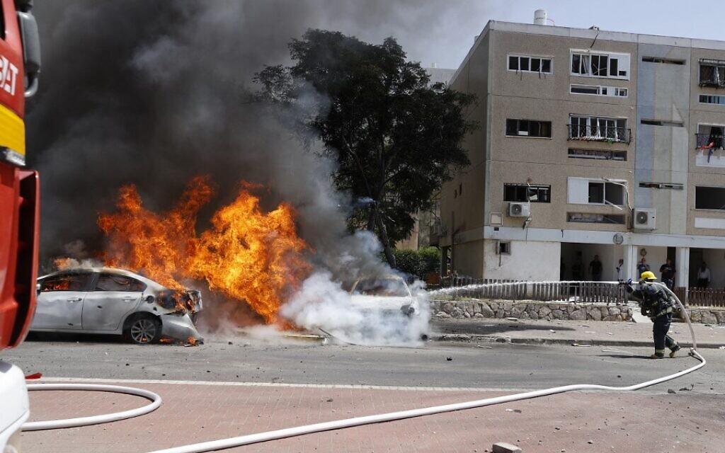 An Israeli firefighter extinguishes a burning vehicle after a rocket launched from the Hamas-run Gaza Strip hit the southern Israeli city of Ashkelon on May 11, 2021. (JACK GUEZ / AFP)