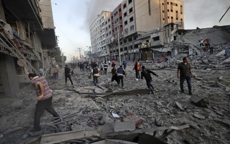 Rescuers and people gather amidst the rubble in front of al-Shourouk tower that collapsed after being hit by an Israeli air strike, in Gaza City, on May 12, 2021 (Mohammed ABED / AFP)