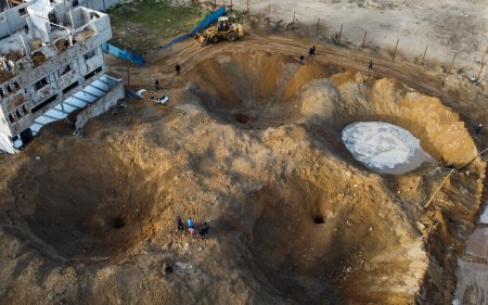 In this aerial picture, Palestinians walk near craters on the ground after Israel launched air strikes on the Hamas-run Palestinian enclave early on April 7, 2023.(MOHAMMED ABED / AFP)