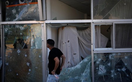A man inspects damage to a bank from a rocket fired from Lebanon in Shlomi, northern Israel, April 6, 2023. The branch was closed for Passover. (AP Photo/Ariel Schalit)